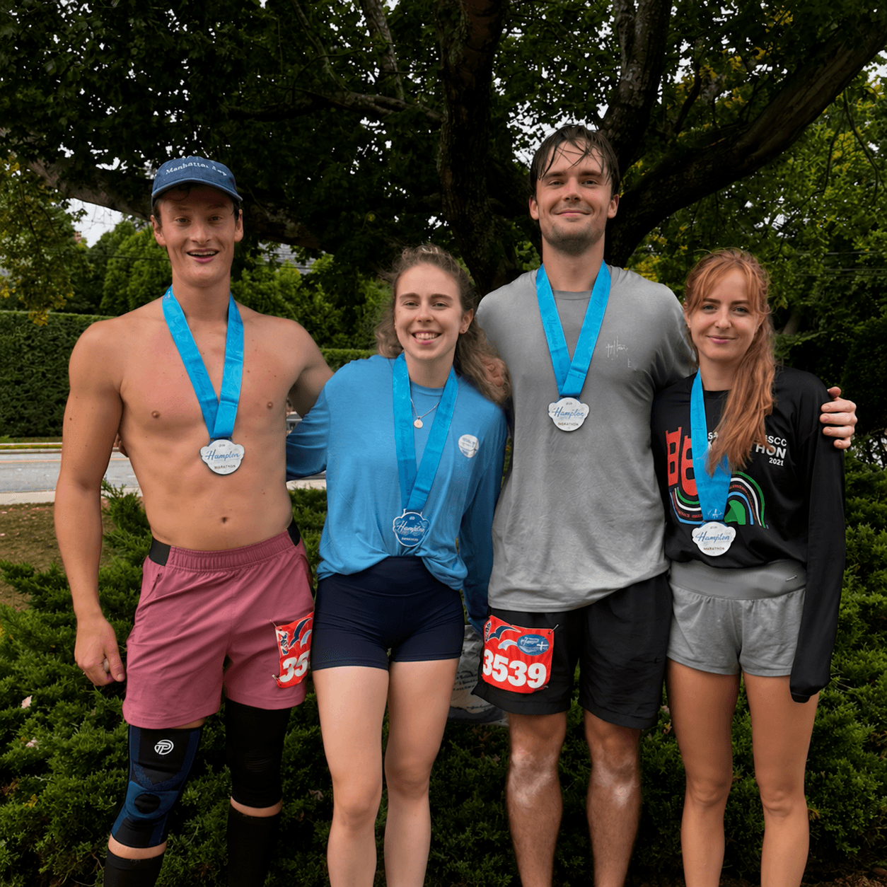 Four runners smiling together with their race medals